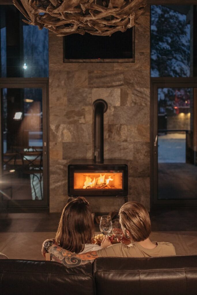 Couple enjoying a romantic evening with wine by a warm fireplace indoors.